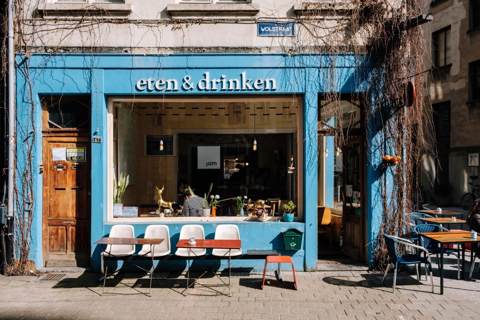 A small cafe with a blue frontage with cafe style seating out the front.